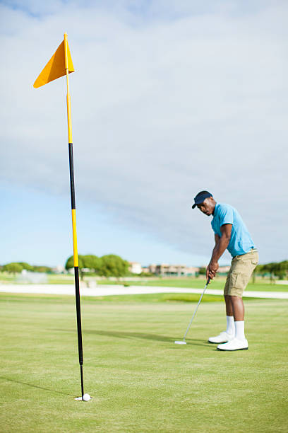 istock African golfer watching his putt role into the hole. 486553191