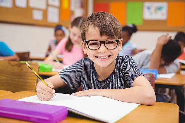 Little boy working at his desk in class stock photo