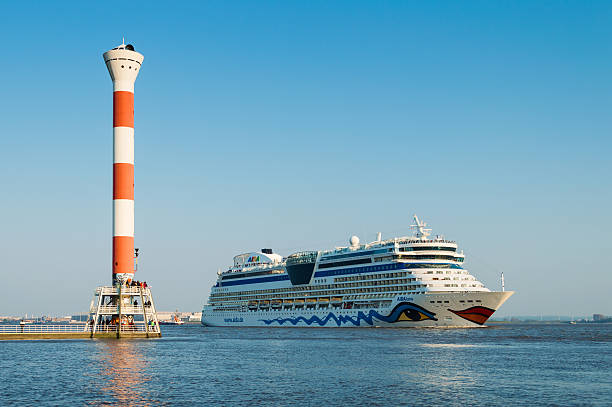 Hamburg, Germany - April 19, 2014: Some spectators are waiting for the cruise ship AIDA luna at the famous lighthouse of Blankenese leaving the harbor of Hamburg - Germany. The AIDA travels along the Elbe until it reaches the North Sea.
