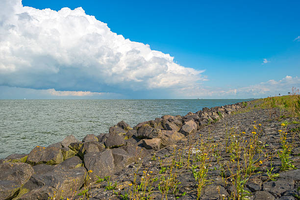 istock Clouds above a lake along a dike in summer 486567826