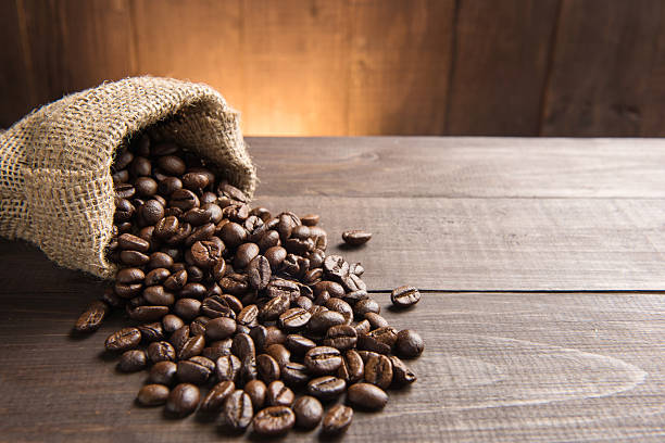 grãos de café em um saco em fundo de madeira. - coffee sack imagens e fotografias de stock