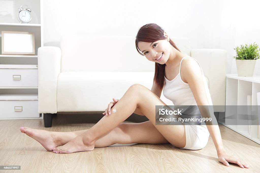 pretty woman applying cream on her attractive legs Beauty of  woman with perfect shape and applying cream on her attractive legs indoors at home,  Women Stock Photo