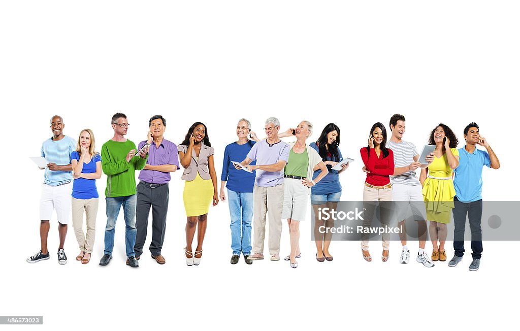 Group of diverse multiethnic  people A group of thirteen multi-ethnic men and women stand in a line next to one another.  They are talking on mobile phones, using computer tablets and smiling.  There is a white background behind them. Active Seniors Stock Photo