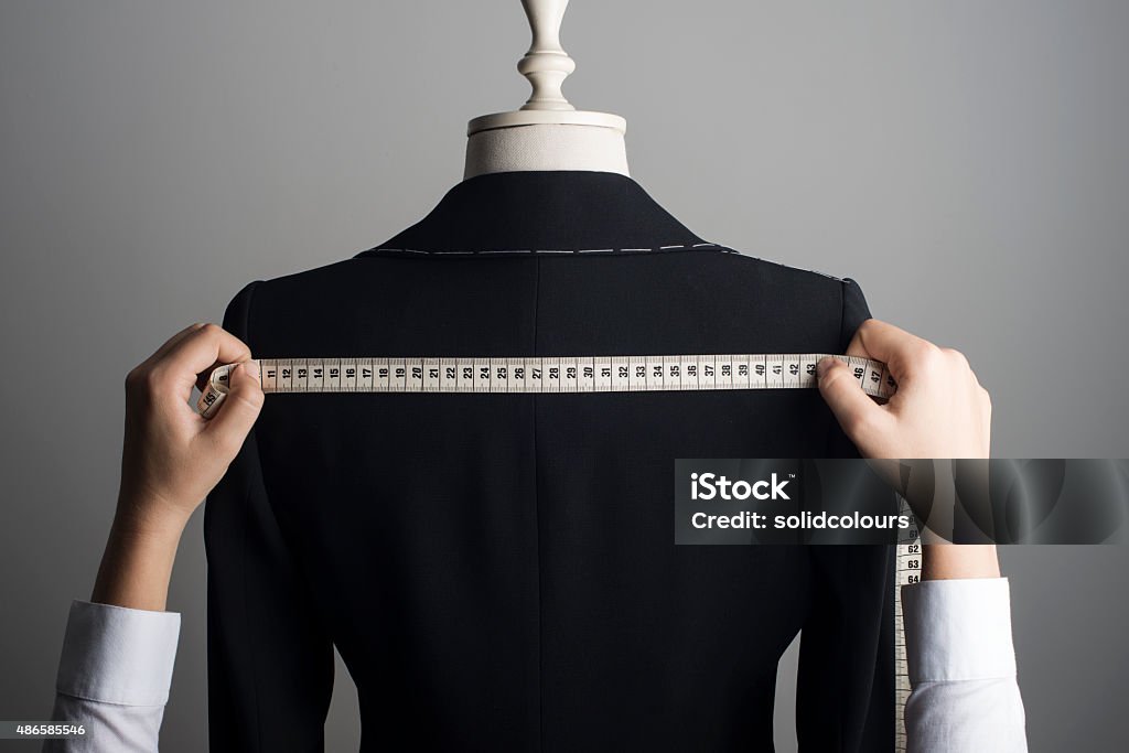 Woman Measuring Jacket on Male Dress Form Woman measuring jacket on tailor mannequin. Tailor Stock Photo