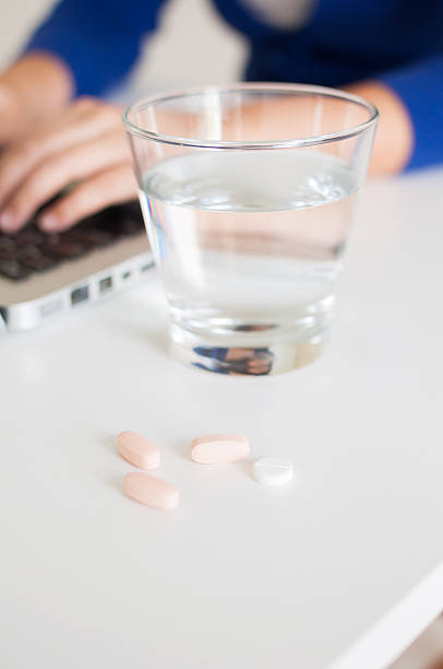 istock Vitamin pills with glass of water while working 486590058