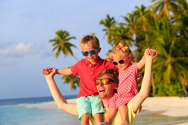 istock father with two kids on shoulders having fun at beach 486591382