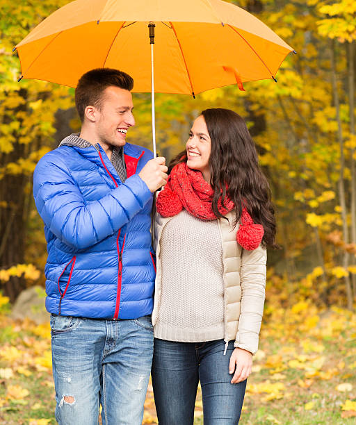 istock smiling couple with umbrella in autumn park 486591386