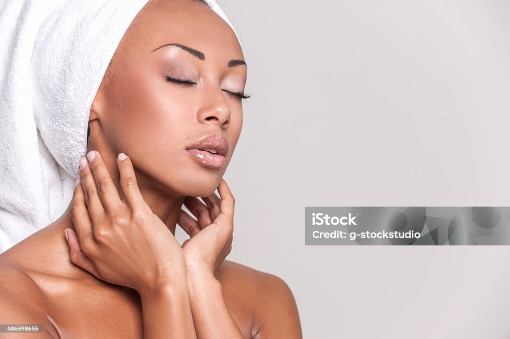 Pure beauty. Beautiful young Afro-American shirtless woman touching her face and keeping eyes closed while Isolated on gray background Naked Stock Photo