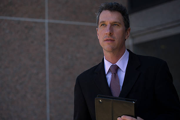 pensive mature businessman outside an office building - foto’s van leiderschap stockfoto's en -beelden