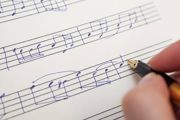 Hand with pen and music sheet Hand pointing with pen to music book with handwritten notes composer photos stock pictures, royalty-free photos & images