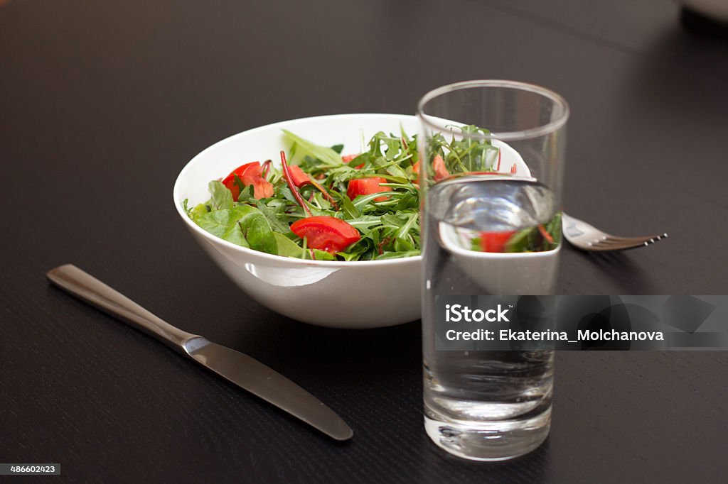 Healthy meal Serving with light salad with tomatoes in white china bowl and a glass of water Antioxidant Stock Photo