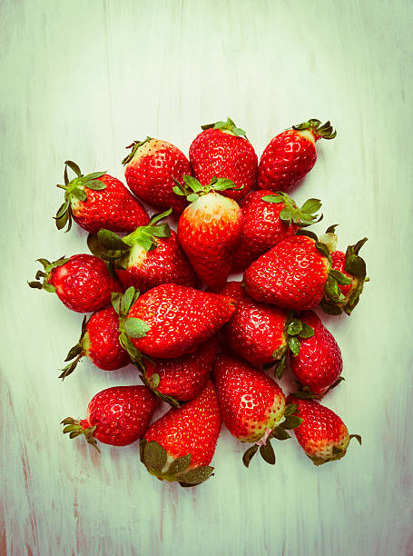strawberries heap on wooden background, top view, toned