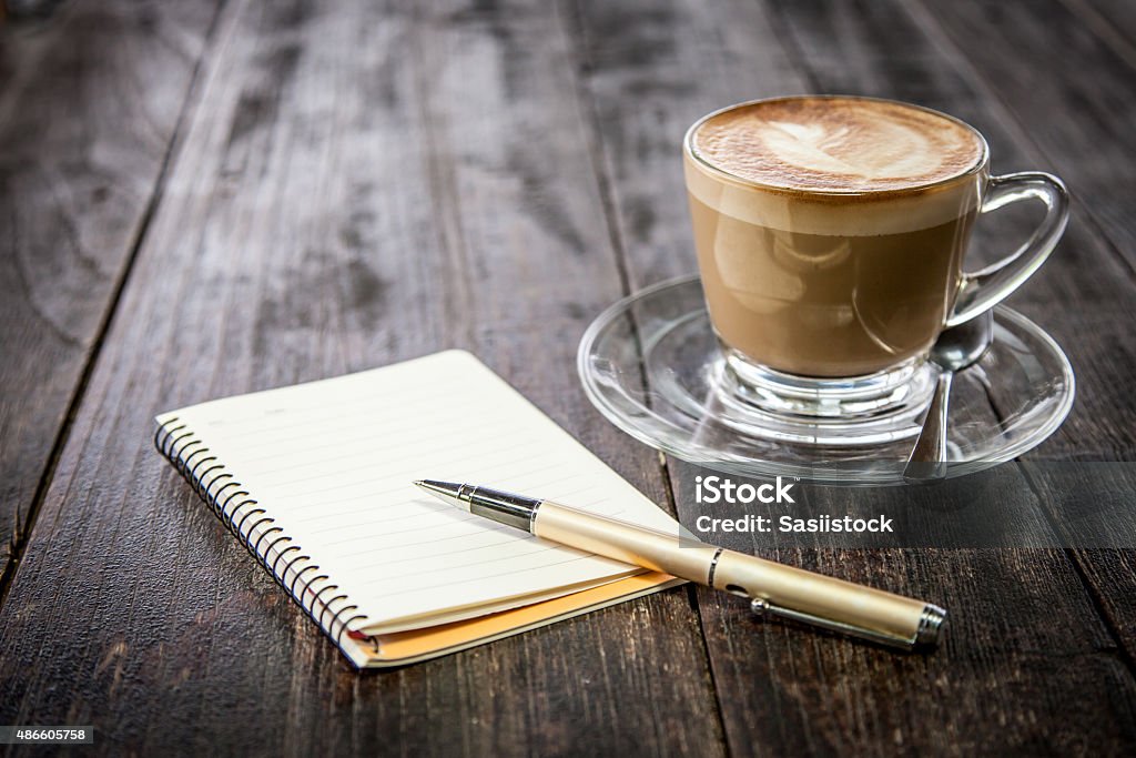 Pen on notebook with coffee cup on wooden table background 2015 Stock Photo