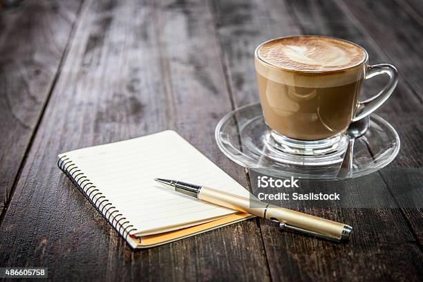 Pen On Notebook With Coffee Cup On Wooden Table Background Stock Photo - Download Image Now