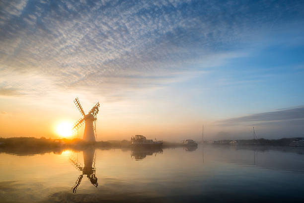 Stunnnig landscape of windmill and river at dawn stock photo