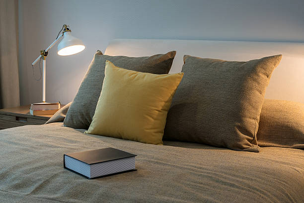 istock Cozy bedroom interior with pillows and reading lamp 486620670