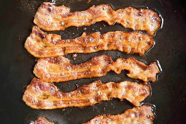 Bacon strips being cooked in frying pan. Close up.