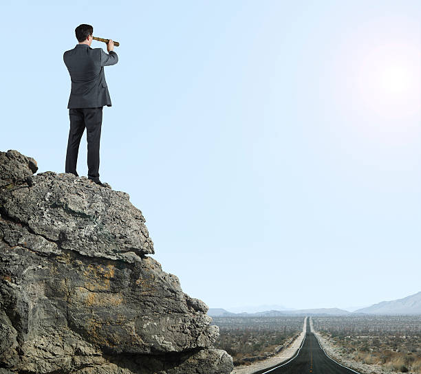 istock Businessman looking through spyglass in the desert 486621421