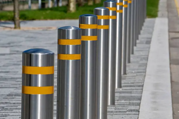 Row of metal bollards with bands of reflective material, positioned at the side of the road 