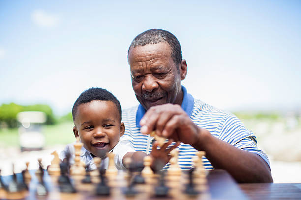 abuelo africano jugando al ajedrez con su nieto - abuelo y bebe fotografías e imágenes de stock