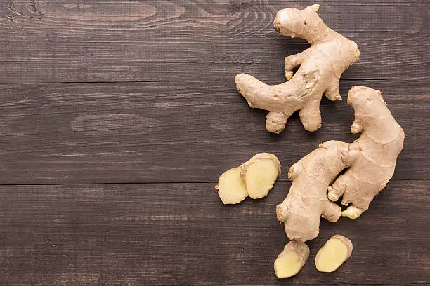 Photo of Ginger root on the wooden background. Top view