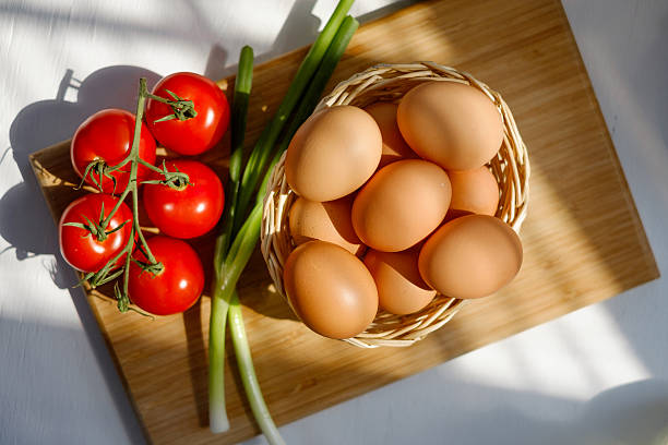 Basket of Eggs with a Bunch of Tomatoes stock photo