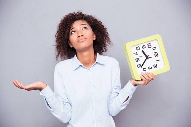 istock Tired afro american woman holding clock 486627878