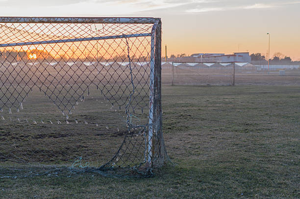 Abandoned soccer field and old rusty goals on sunset