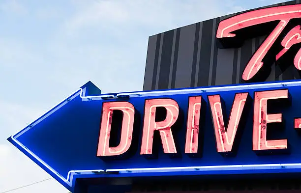 Neon road sign for drive-in movie theatre in New York State, USA.