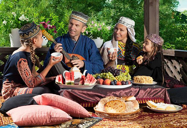 Playing mandolin The head of the family playing mandolin while having breakfast. Whole family dressed in Central Asian clothes. uzbekistan stock pictures, royalty-free photos & images