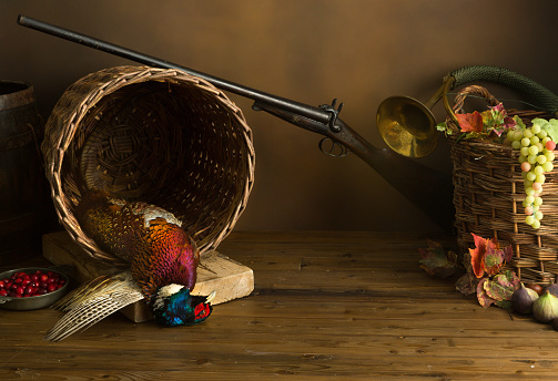 Hunting still life with pheasant, basket and fruit.
