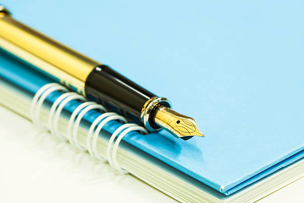 istock Gold fountain pen on notebook 486640226