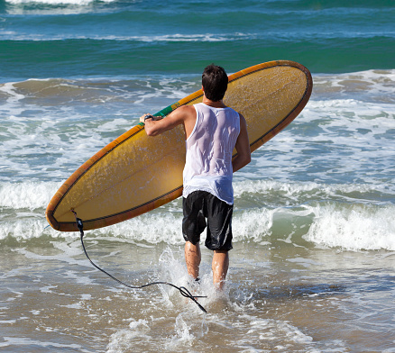 Portrait of Surfer with longboard on the beach.