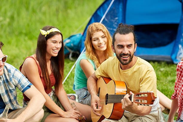 istock happy friends with drinks and guitar at camping 486647380