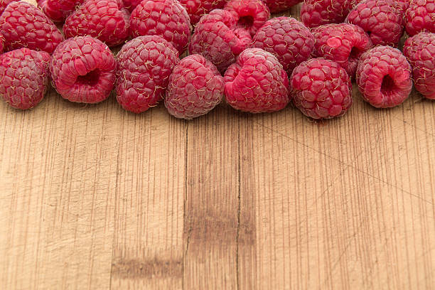 istock Ripe sweet raspberries on wood table close-up 486647444