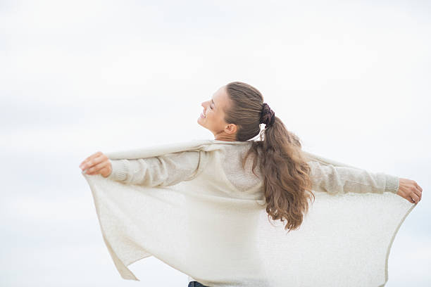 istock young woman on cold beach rejoicing. rear view 486647625