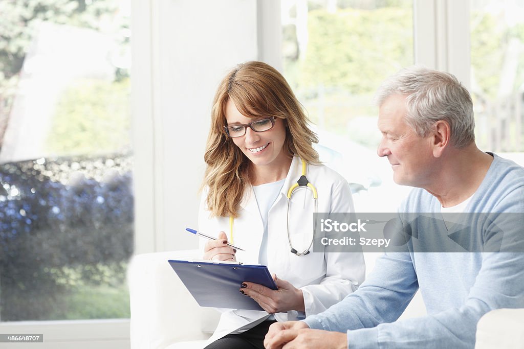 Analyzing x-ray Beautiful female doctor analyzing x-ray with senior patient at small clinic. Female Doctor Stock Photo