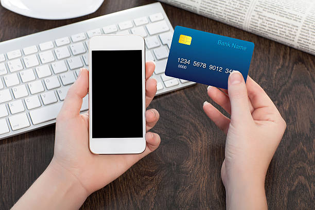 istock female hands holding phone and credit card over the table 486649321