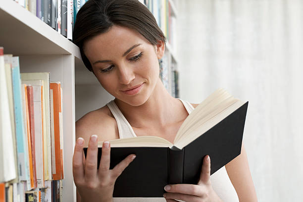 femme lisant en bibliothèque à la maison - herne bay photos et images de collection