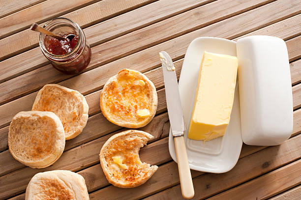 English Muffins, Butter and Jam on Wooden Table High Angle View of Toasted English Muffins with Butter and Jam on Top of Wooden Table english muffin stock pictures, royalty-free photos & images