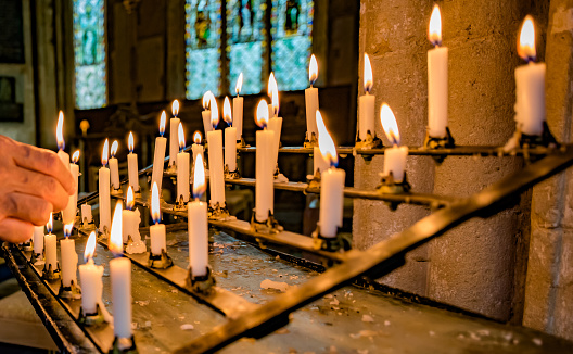An individual is lighting a prayer candle in church.