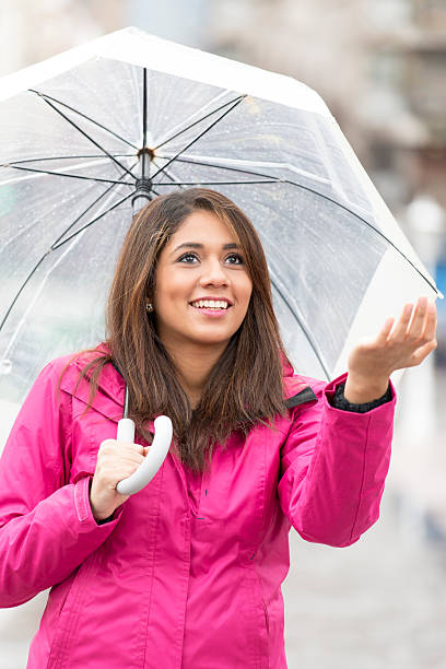 istock Smiling young woman with umbrella checking for rain. 486660694
