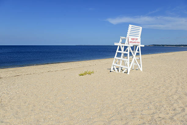 White lifeguard chair on empty sand beach with blue sky