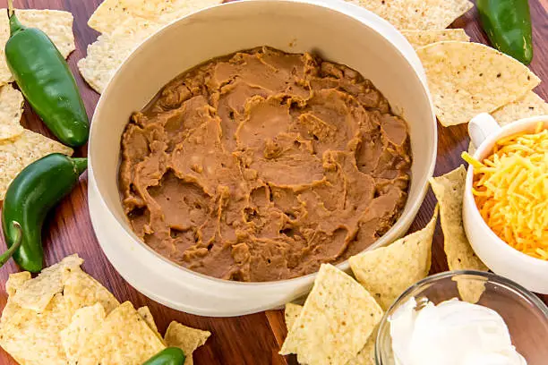 preparation of layered bean dip with jalapenos, sour cream and cheddar cheese