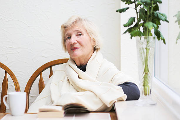 istock Senior woman drinking coffee and reading book indoors 486666891
