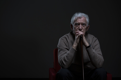 Thoughtful elder man sitting in a dark room