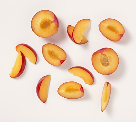 Slices of plum on a white background with shadows