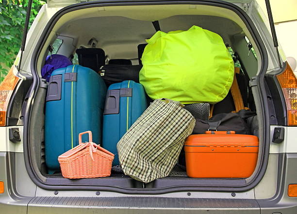 twosuitcases and many bags in the trunk of the car ready to depart