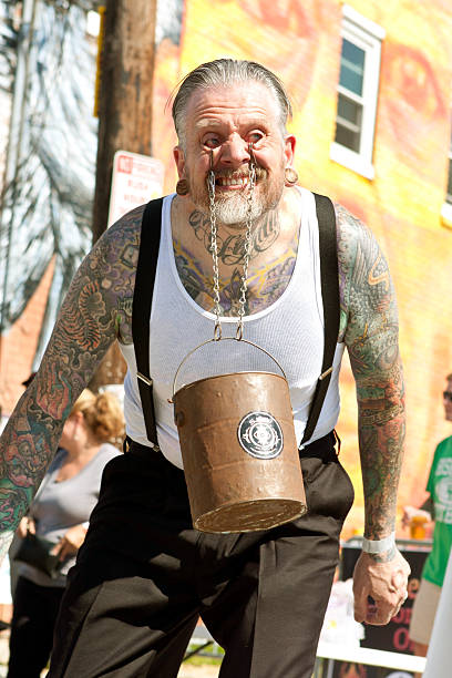 Atlanta, GA, USA - May 2, 2015:  A man swings a bucket filled with bricks, by using chains hooked to the inside of his eyelids, while performing in a freak show at the Fire In The Fourth festival in Atlanta.