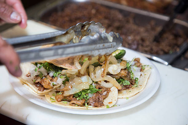 istock Cook putting grilled onions on fresh made chicken tacos 486674329
